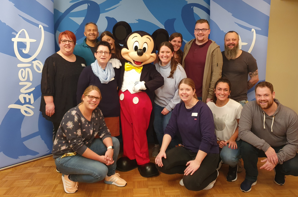 Einzigartiger Besuch in der KJPP in Aschendorf: Mitarbeiter freuen sich über ein Foto mit Mickey Mouse